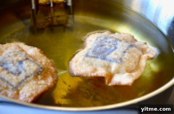 A pot of hot oil with several golden brown chocolate wontons being deep-fried to perfection.