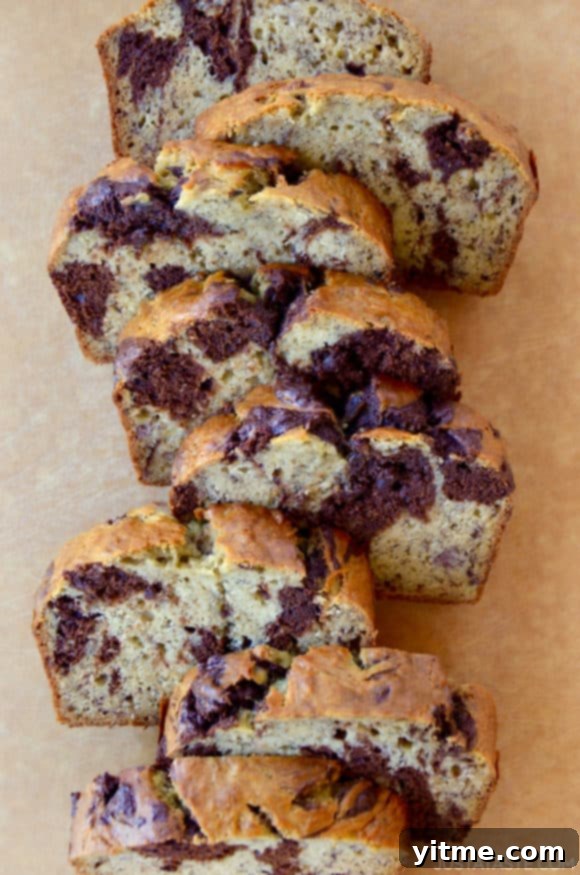 Chocolate Swirl Banana Bread sliced on a wooden cutting board, showcasing rich chocolate veins