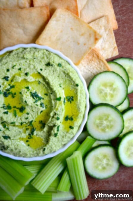 Vibrant green creamy edamame and pea hummus garnished with fresh parsley.