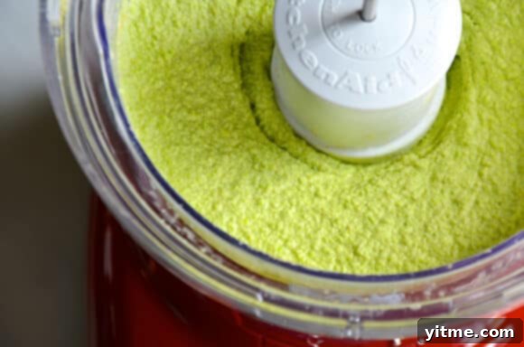 Various crackers and vegetable sticks served alongside a bowl of creamy edamame and pea hummus.