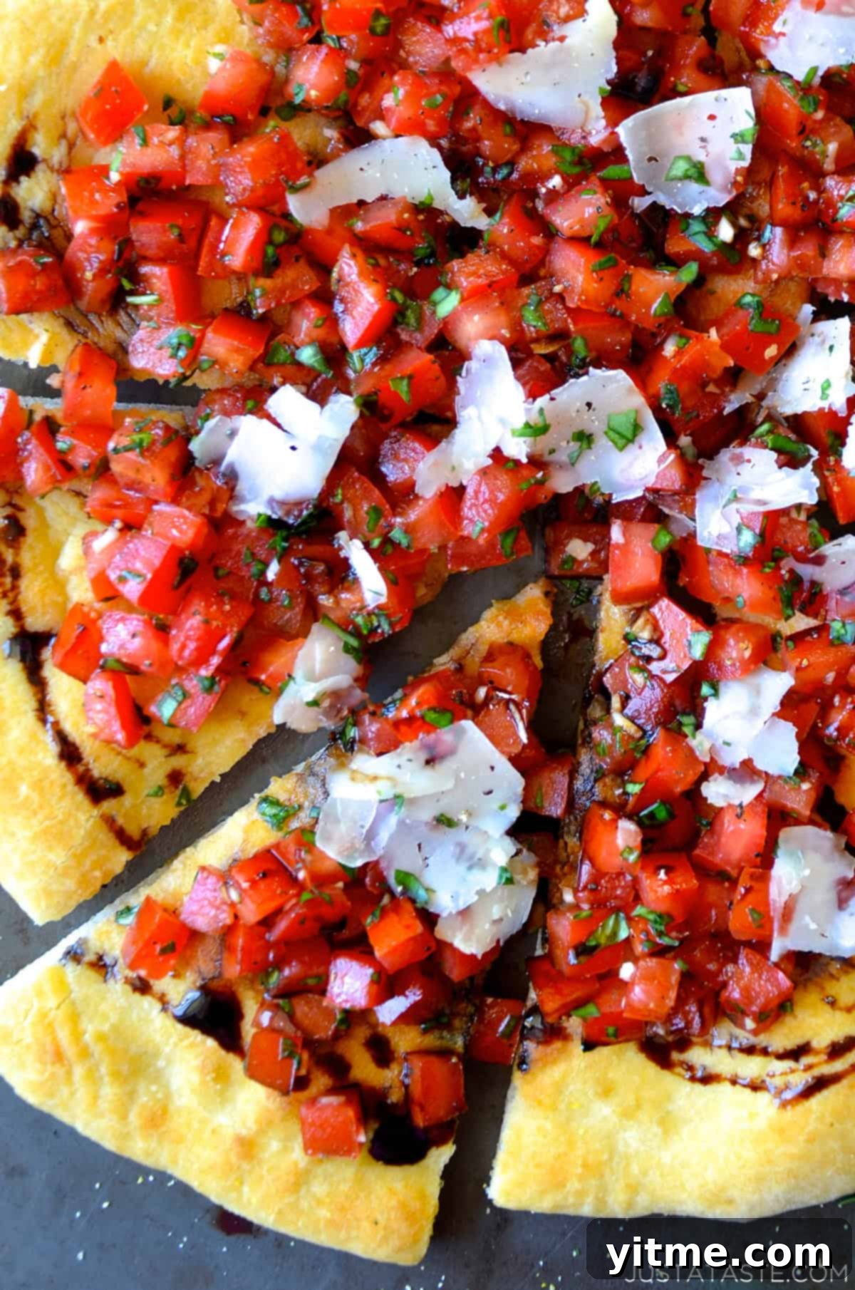 Tomato bruschetta pizza topped with homemade balsamic glaze and shaved Parmesan cheese.