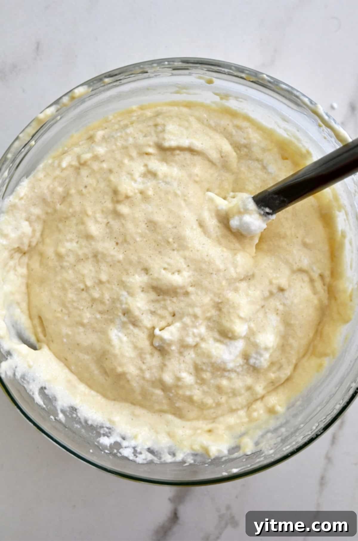 Golden Belgian Waffles From Scratch 8 Whipped egg whites folded into a buttermilk waffle batter in a large glass bowl.