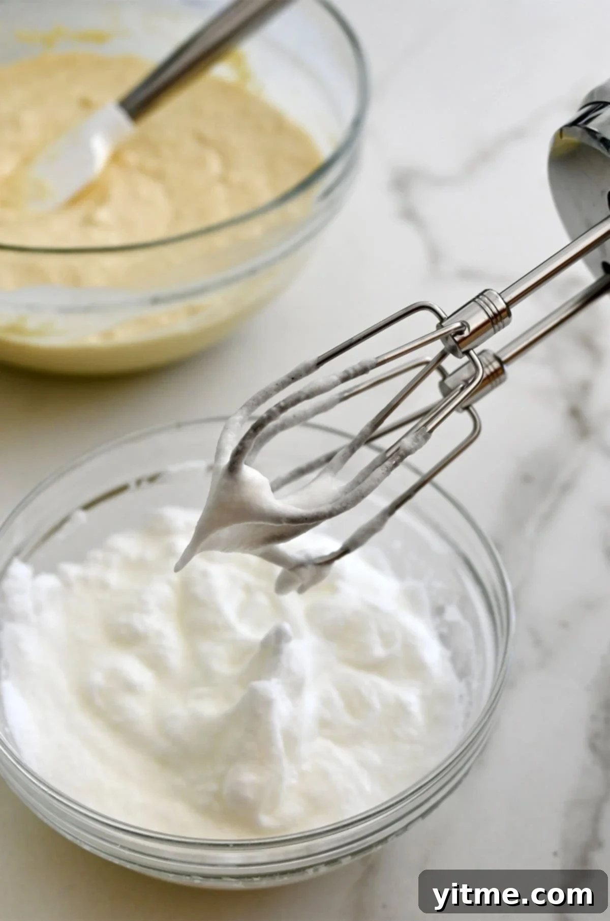 Golden Belgian Waffles From Scratch 9 An electric mixer hovers over a bowl containing whipped egg whites.