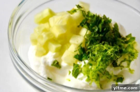 Five-Spice Beef Skewers 5 A clear bowl containing yogurt, diced cucumbers, and lime zest