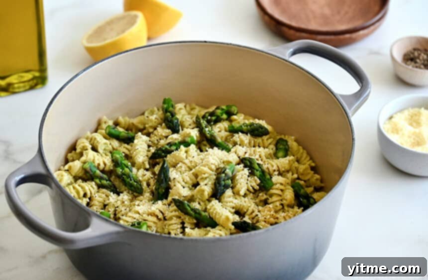 Creamy Asparagus Pesto Pasta 6 Creamy asparagus pesto pasta garnished with asparagus spears and Parmesan cheese in a large stockpot, showcasing the finished dish.