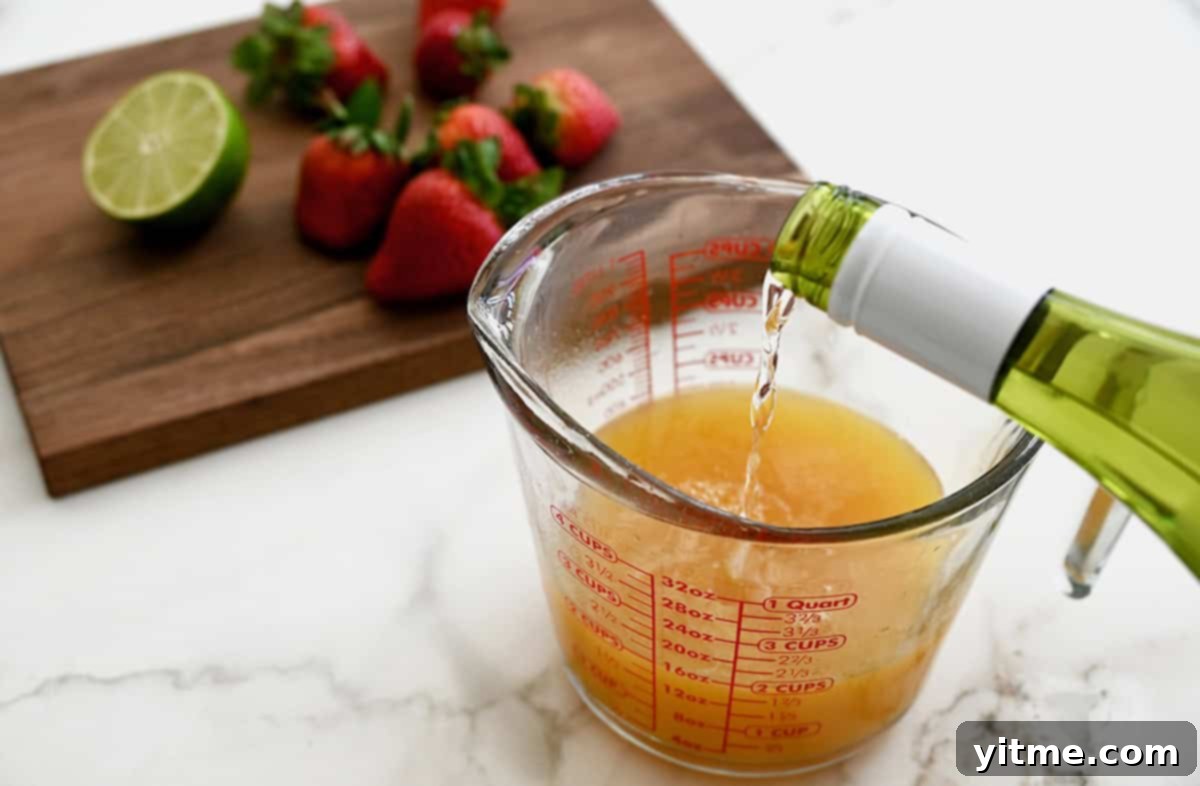 White wine is carefully poured into a liquid measuring cup that already contains peach juice, starting the mixture for sangria popsicles.