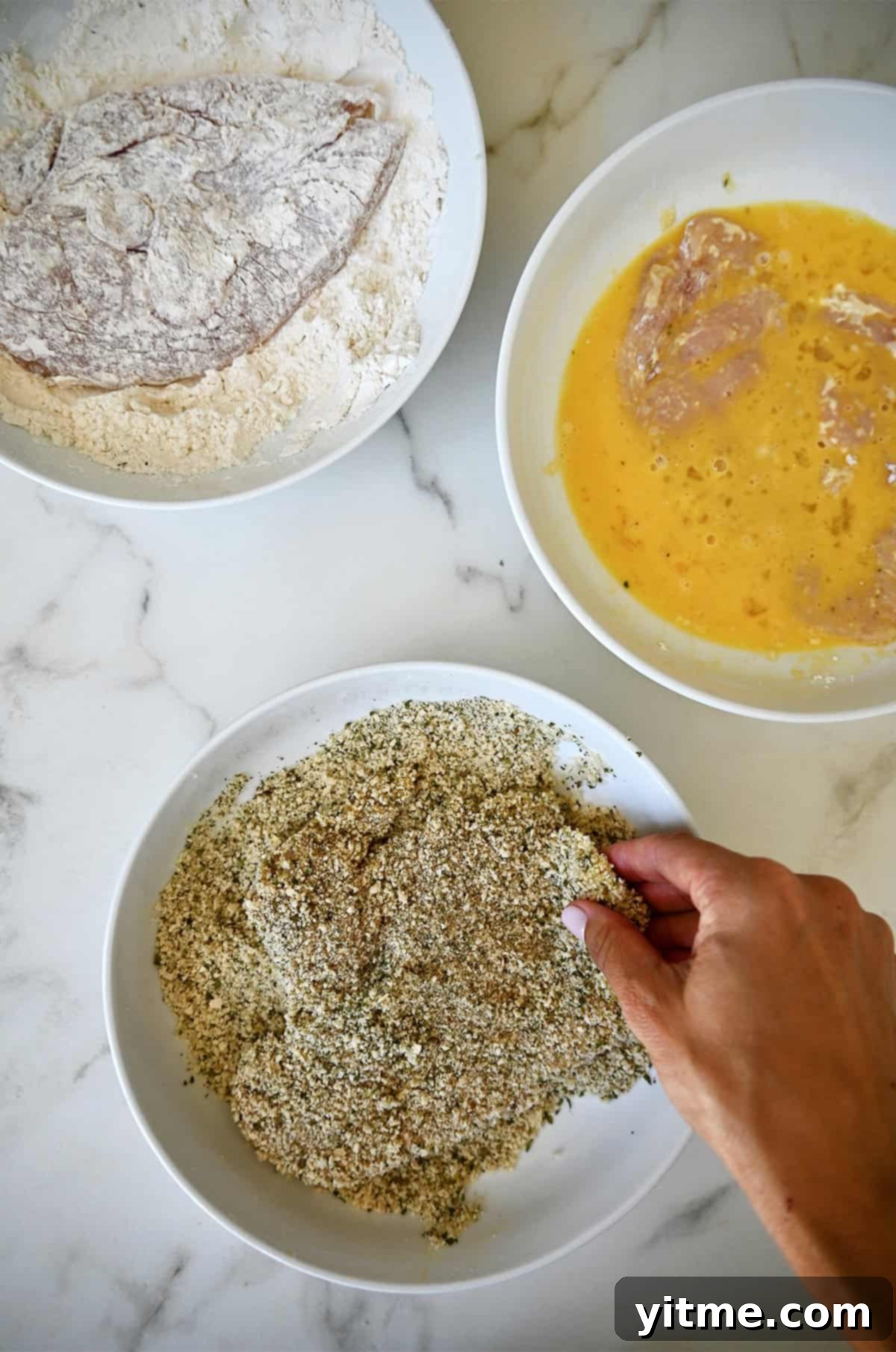 Dredging chicken in flour, eggs, and breadcrumbs for Chicken Milanese