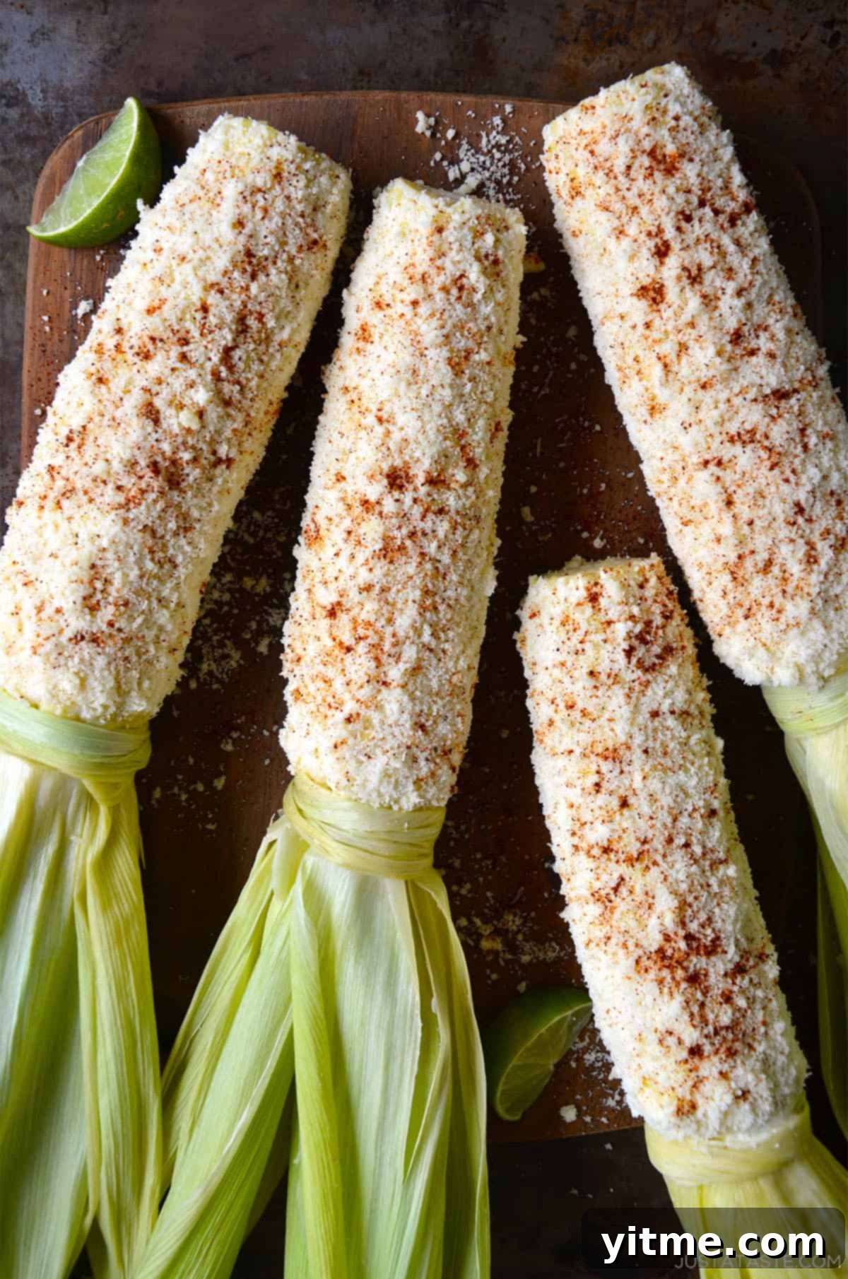 Four ears of Elote, or Mexican street corn, beautifully prepared with a creamy sauce, Cotija cheese, and chili powder. A quintessential summer side dish.