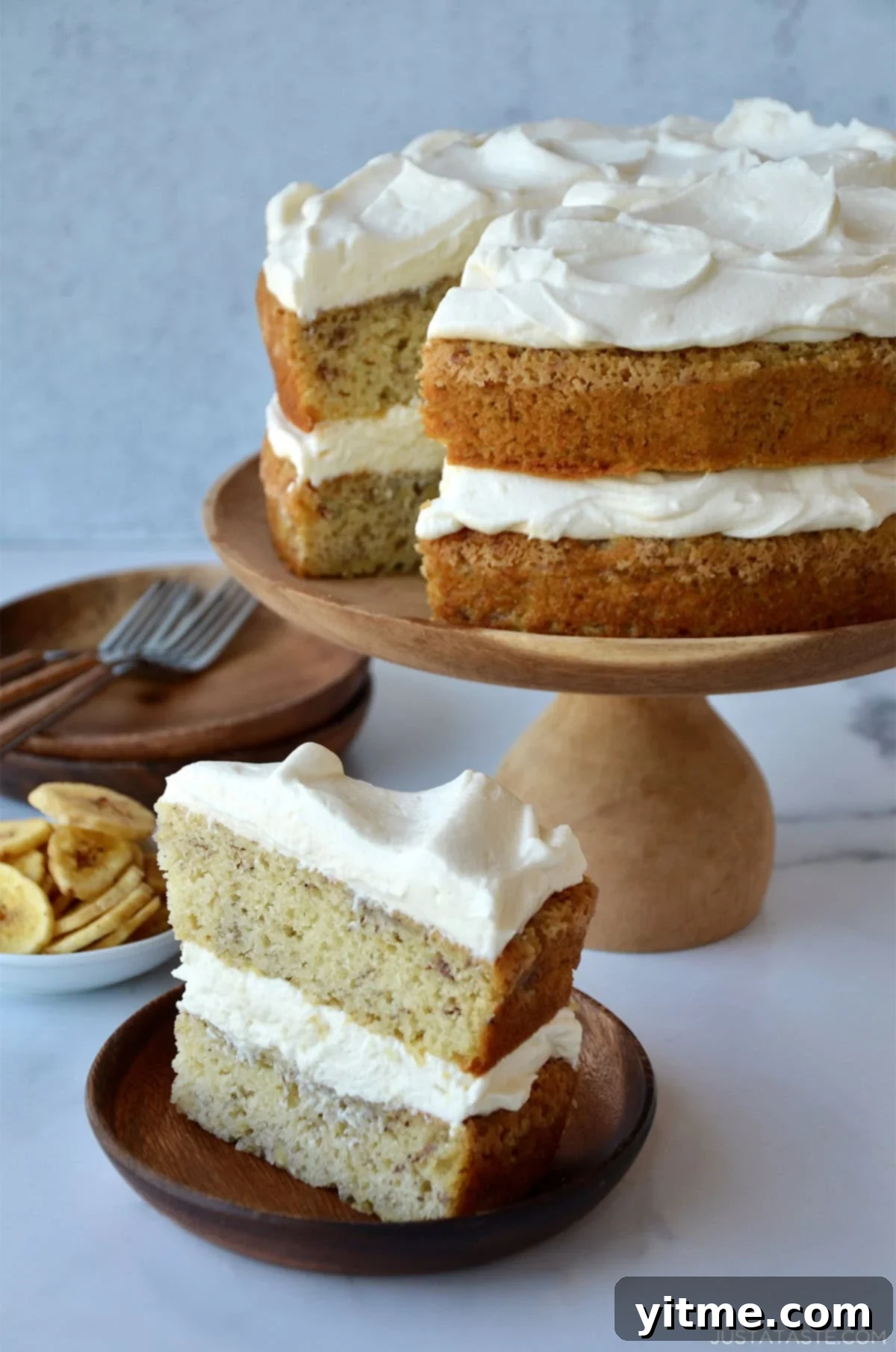 A slice of banana cake with cream cheese frosting on a plate.