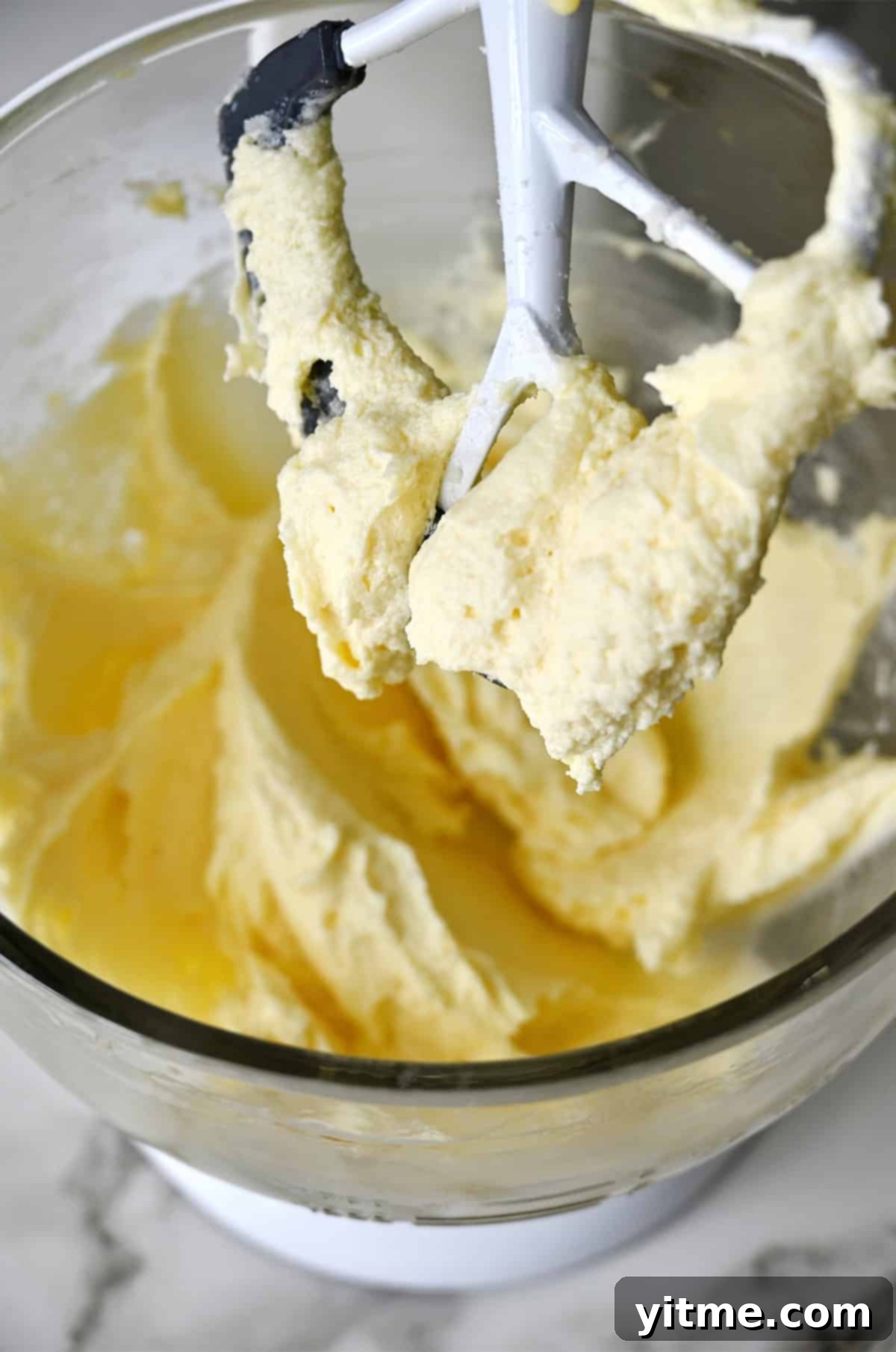 Banana cake batter coating a paddle attachment of a stand mixer.