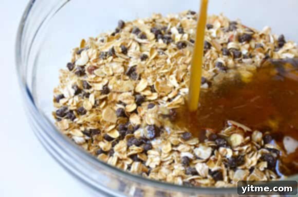 Rolled oats and mini chocolate chips being mixed in a glass bowl.