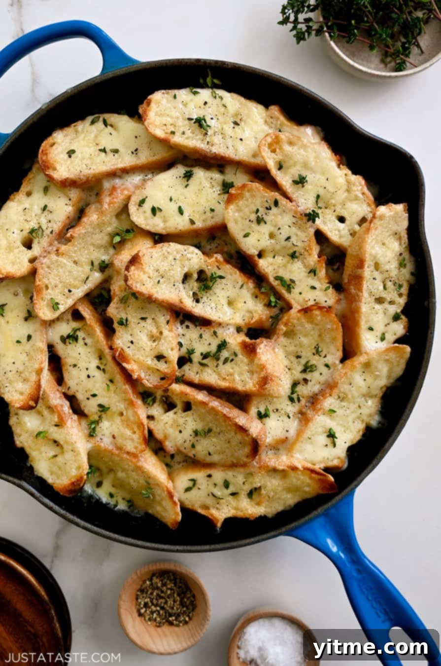 A blue skillet containing cheesy toasts surrounded by small bowls