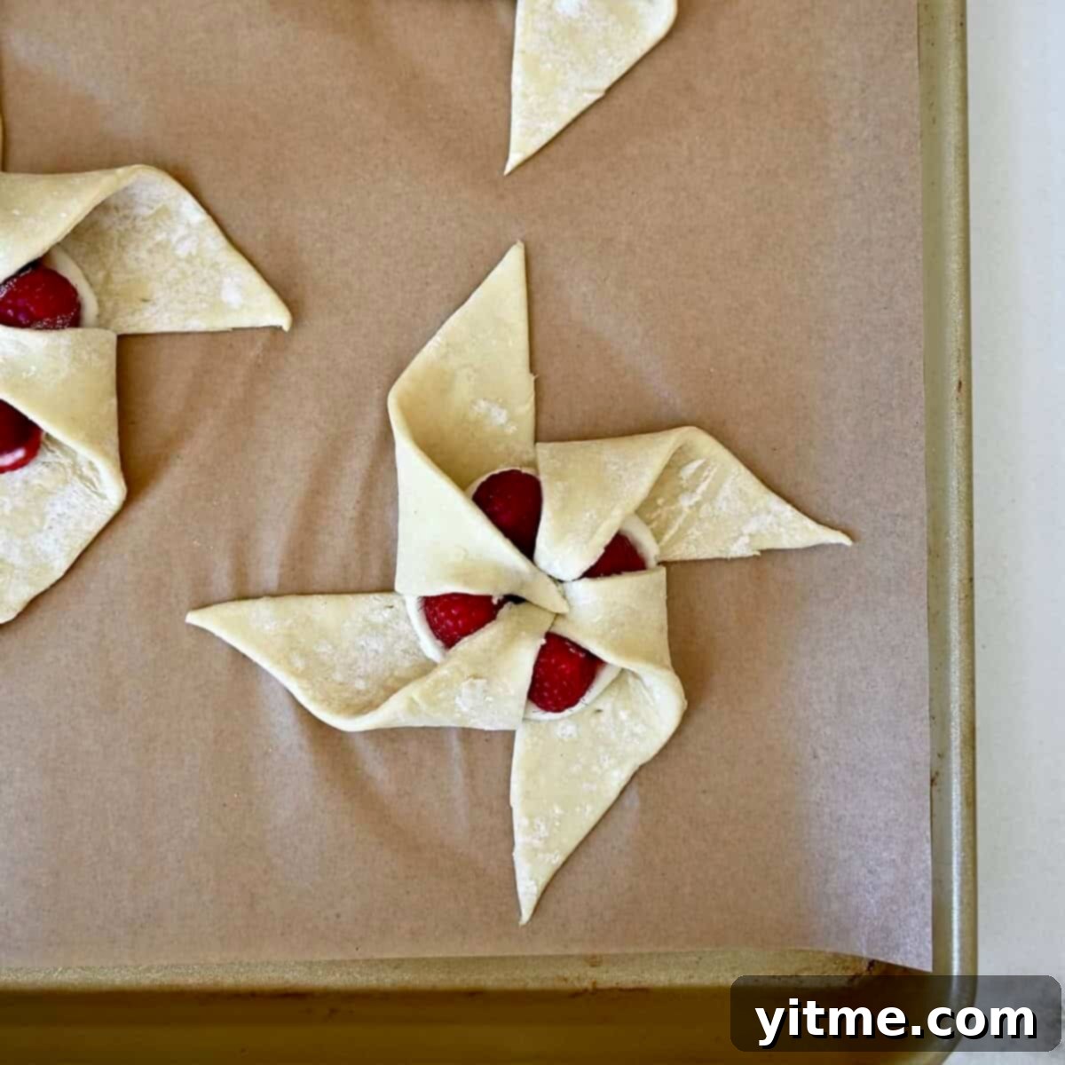 Step 4 of shaping a pinwheel: The final corner folded into place, completing the elegant pinwheel design of the puff pastry.