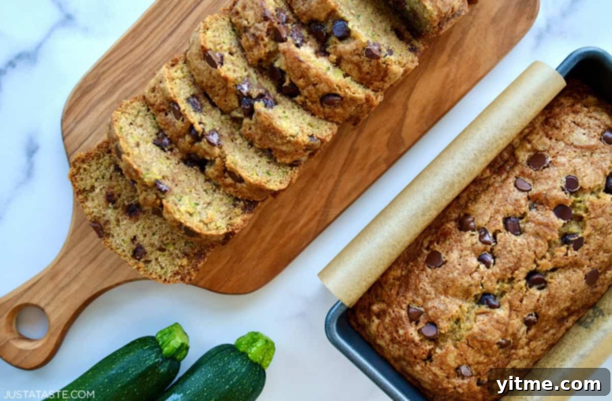 Two loaves of zucchini chocolate chip bread next to two zucchini.