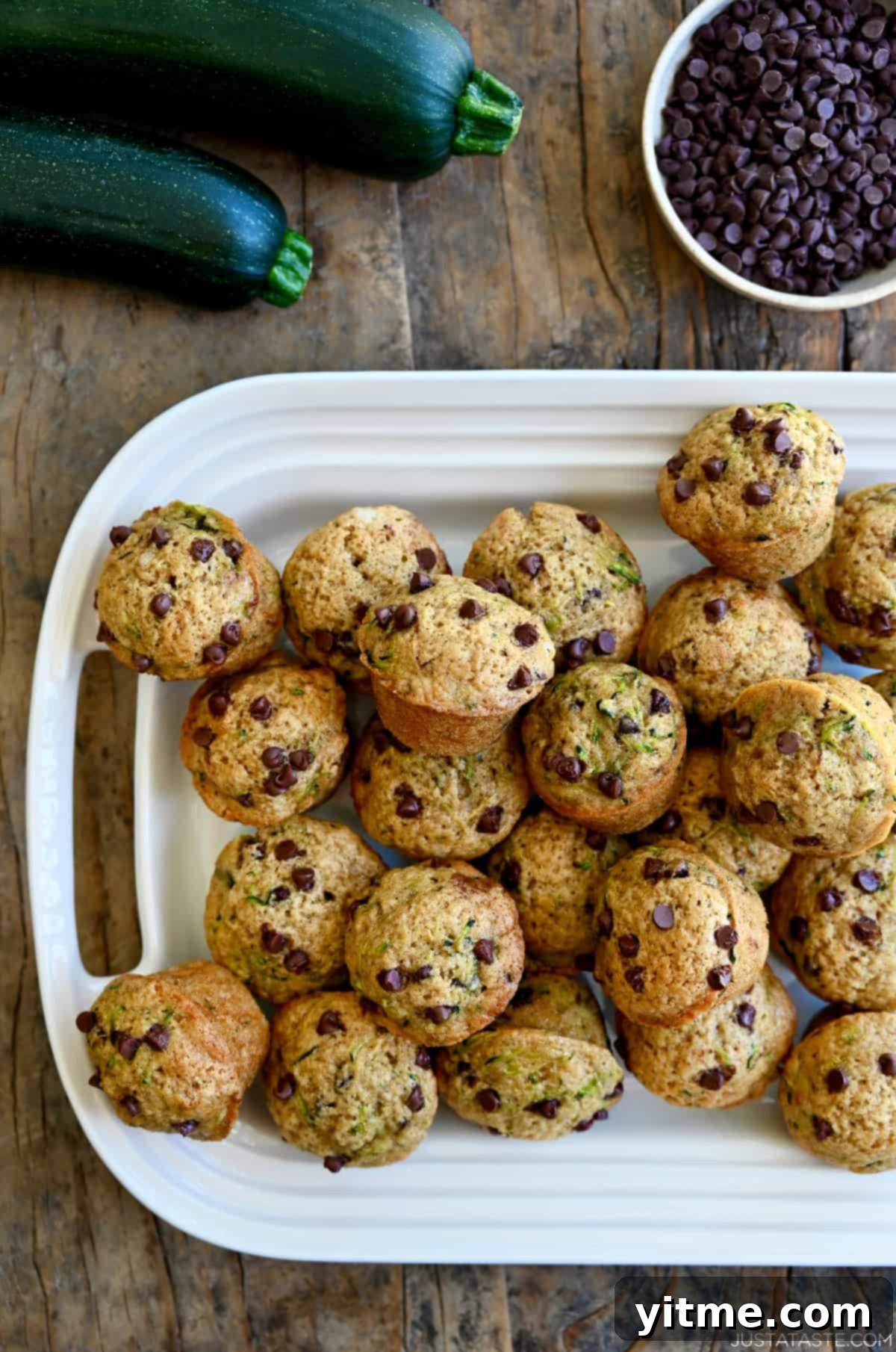 A white serving platter loaded with mini chocolate chip zucchini muffins.