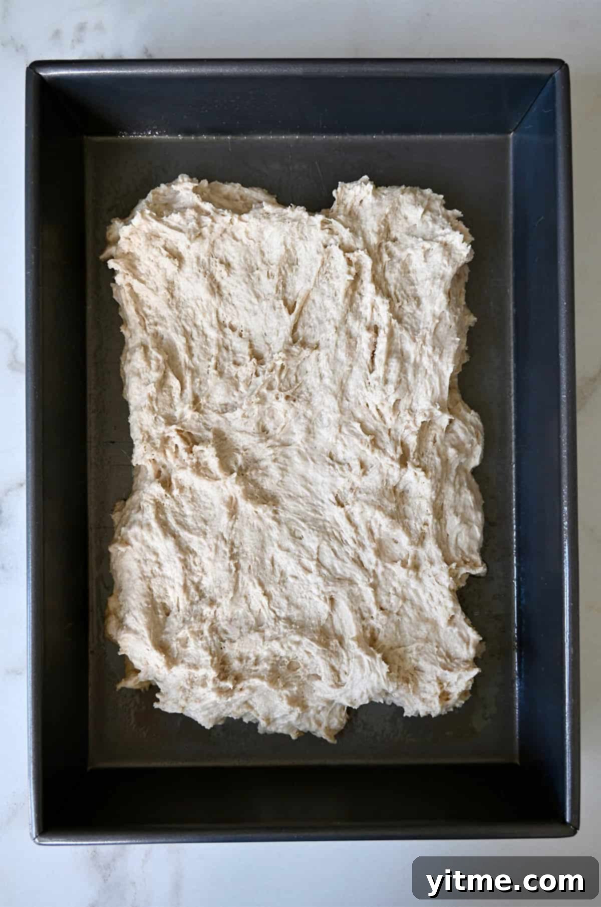 Focaccia dough in a 9x13 baking pan before proofing.