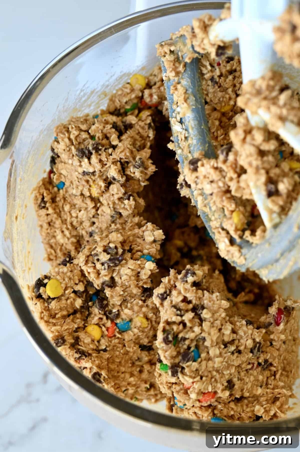 Monster cookie bar dough in the bowl of a stand mixer with the paddle attachment, ready to be transferred.