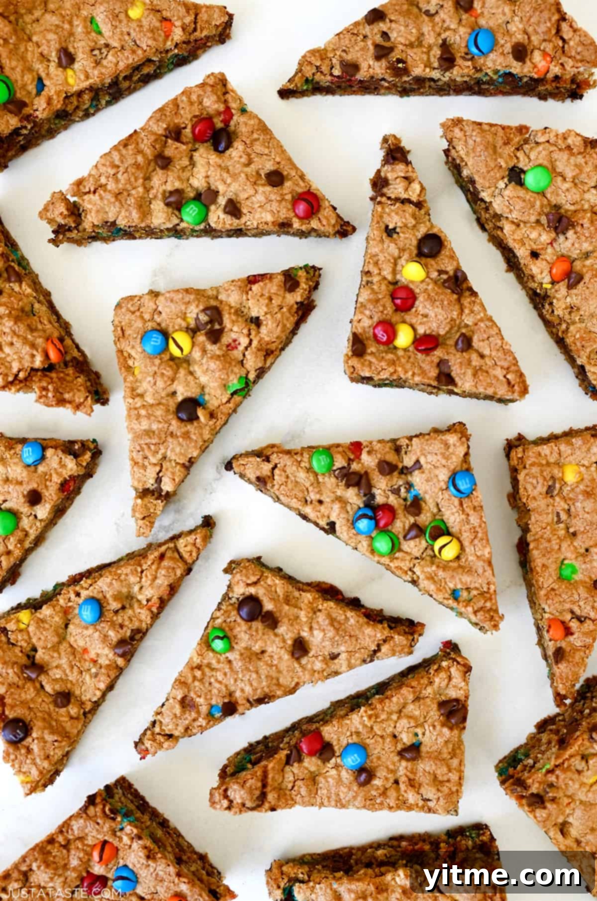 Monster cookie bars studded with M&Ms and chocolate chips cut into triangles.