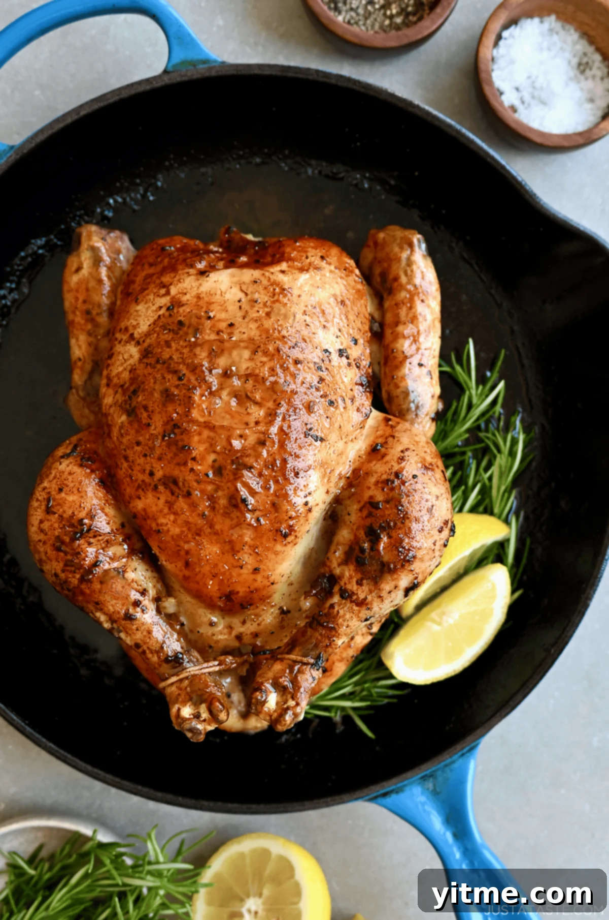 Simple roast chicken with rosemary and lemon in a cast iron skillet. Juicy and golden brown.