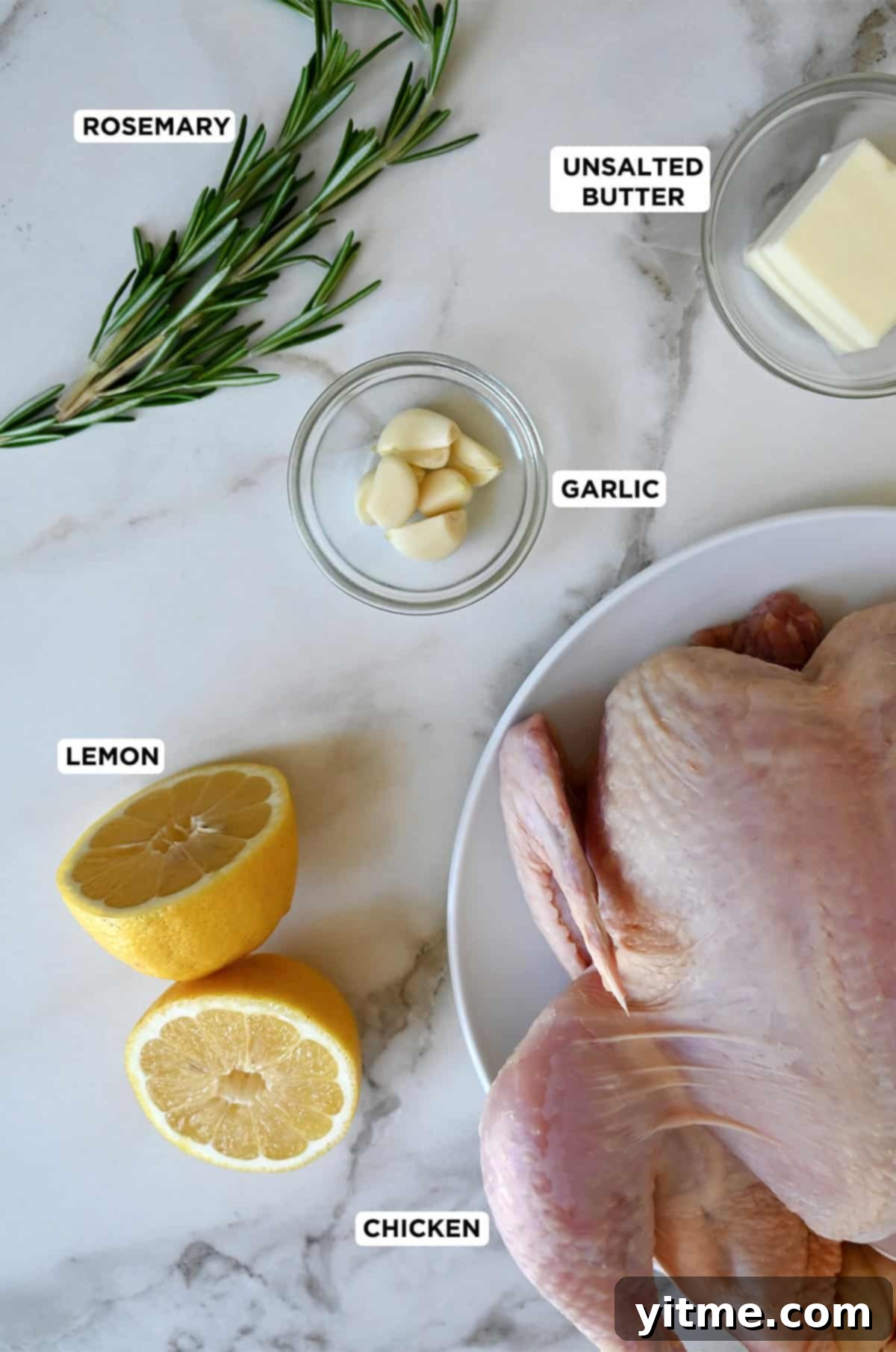 Ingredients for roast chicken: whole chicken, lemon, rosemary, garlic, and butter.