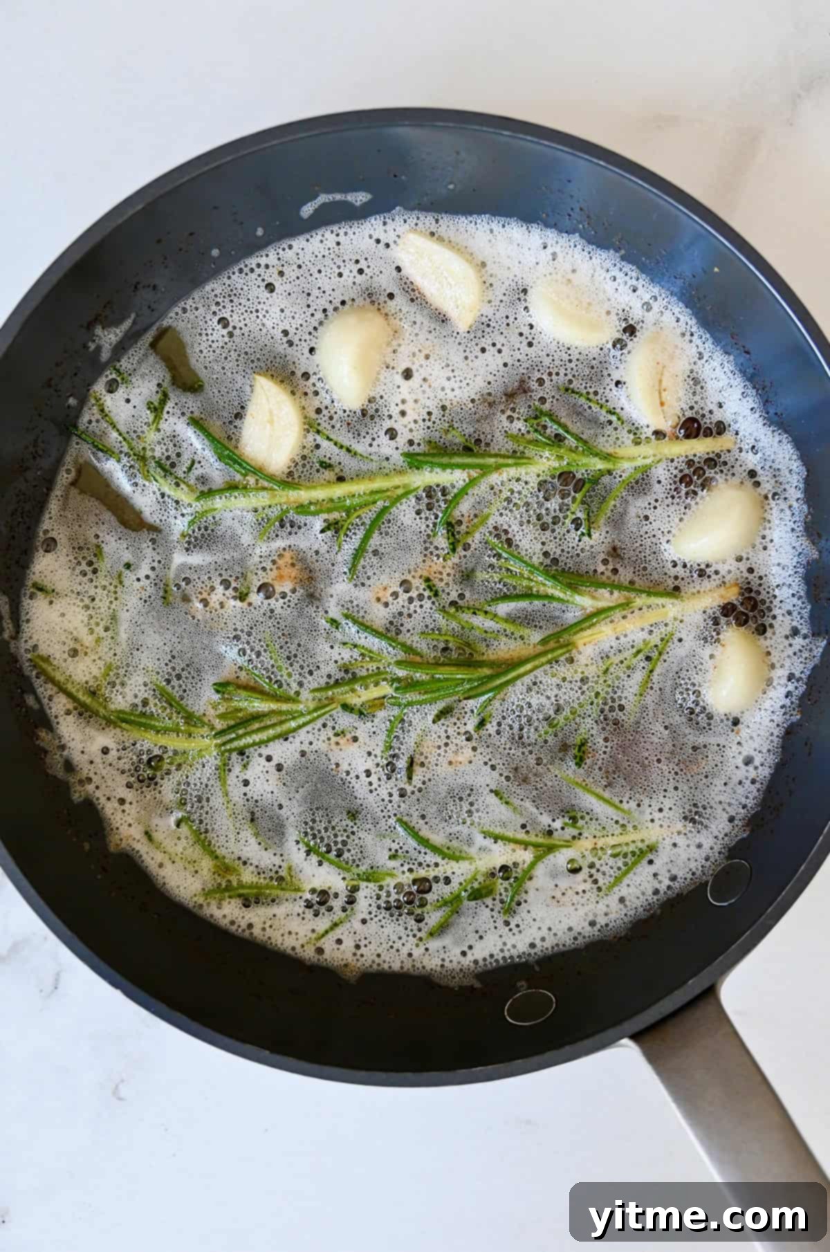 Melted butter with rosemary and garlic in a skillet.