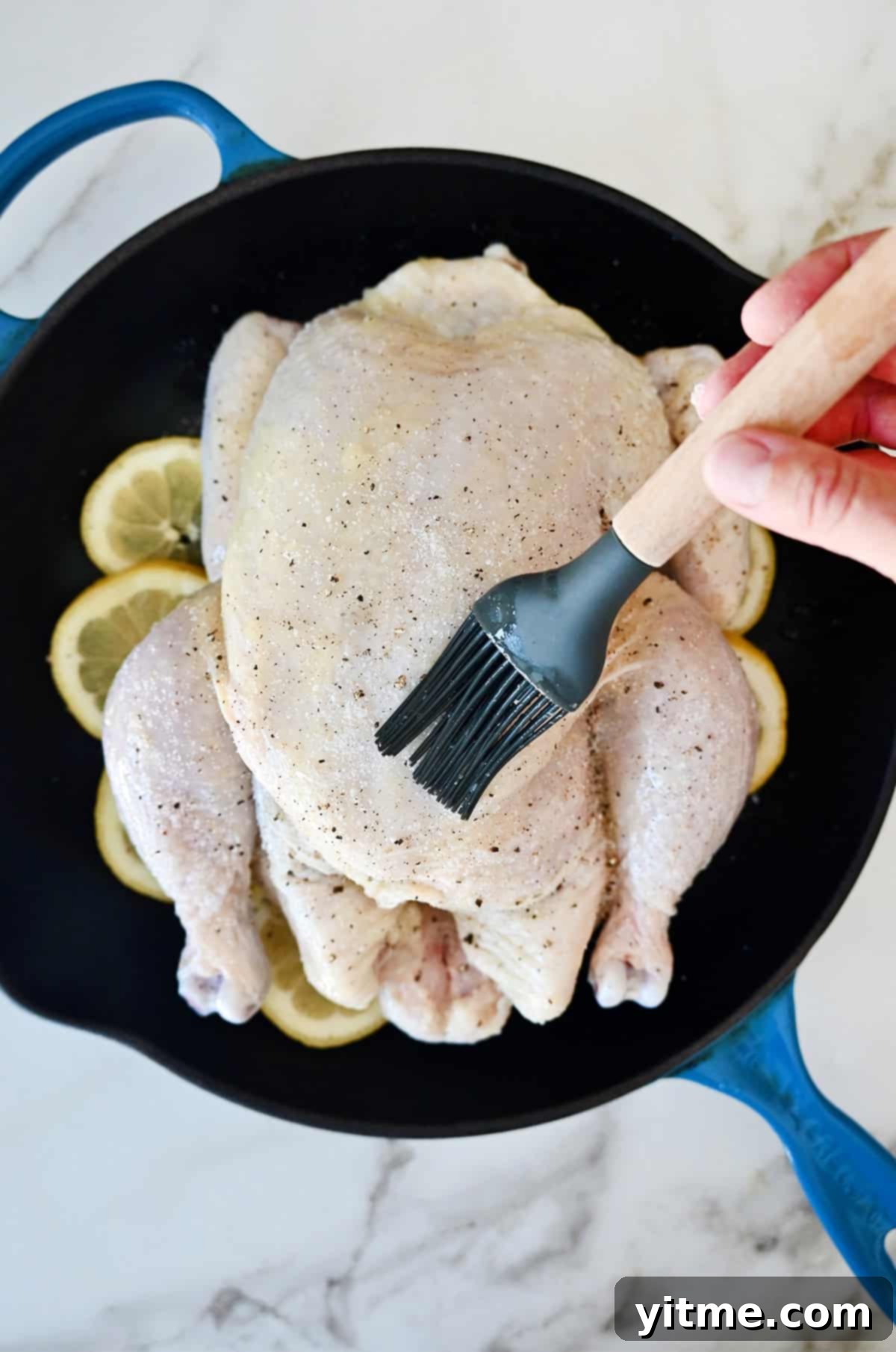 Brushing garlic-rosemary butter on chicken.