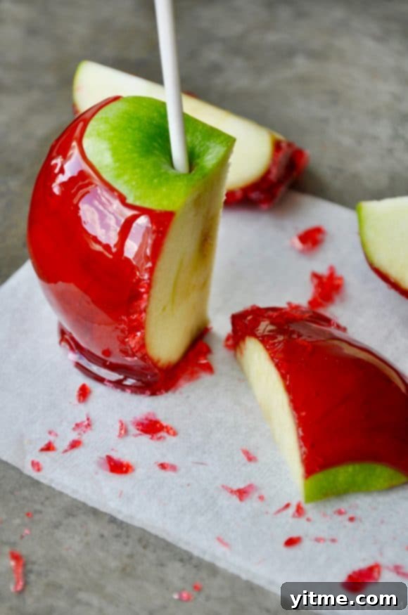A green candy apple sliced on a grey baking sheet