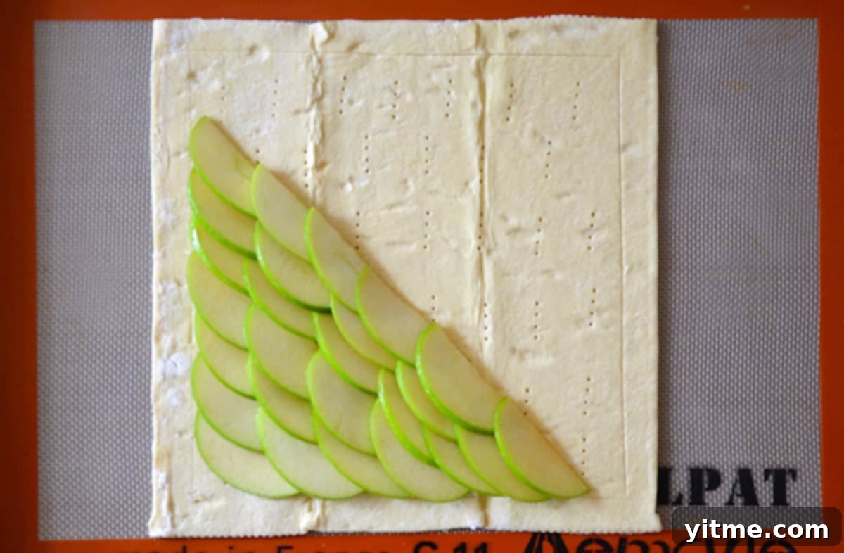 Puff pastry on a Silpat, covered with overlapping apple slices.