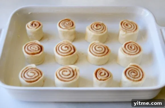 Unbaked cinnamon rolls in a white baking pan