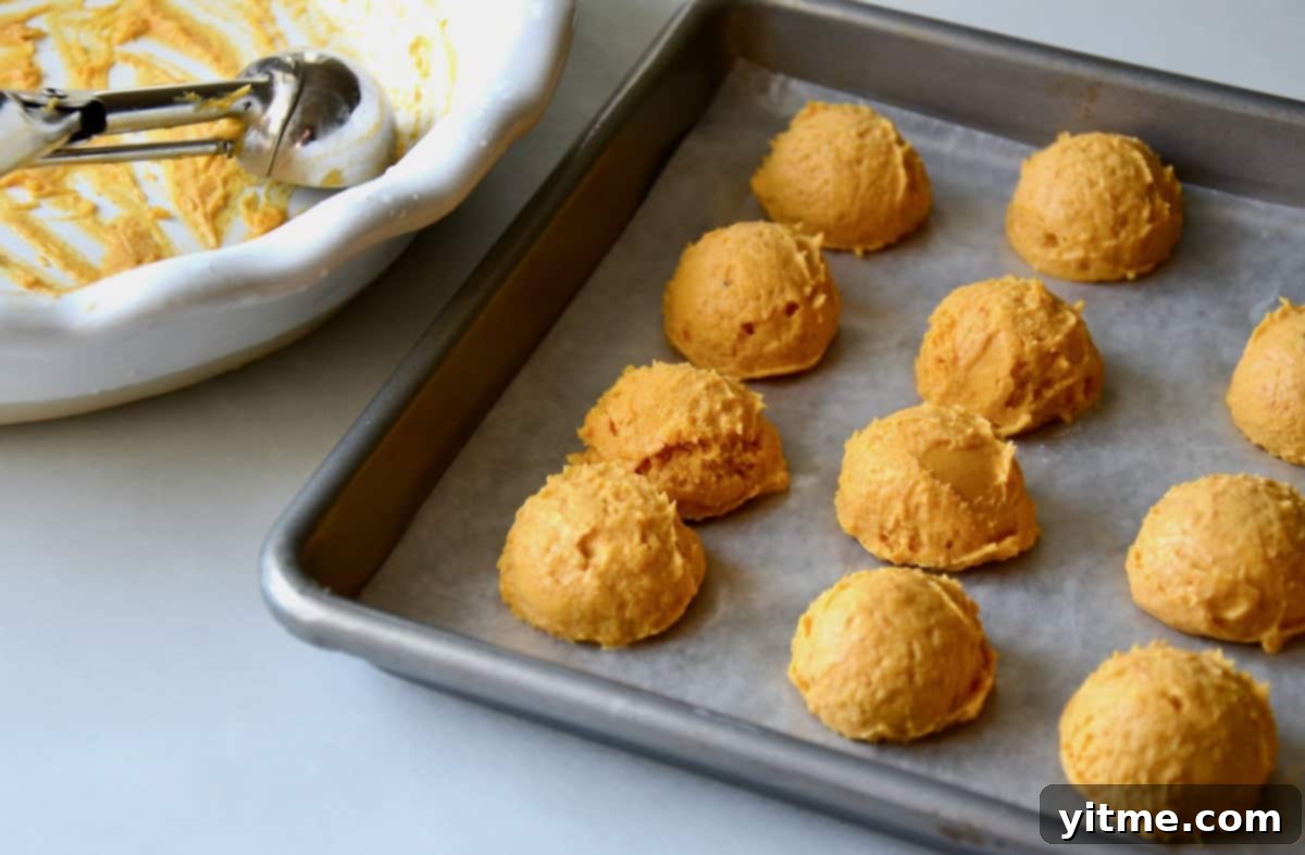 Scoops of pumpkin cheesecake on baking sheet