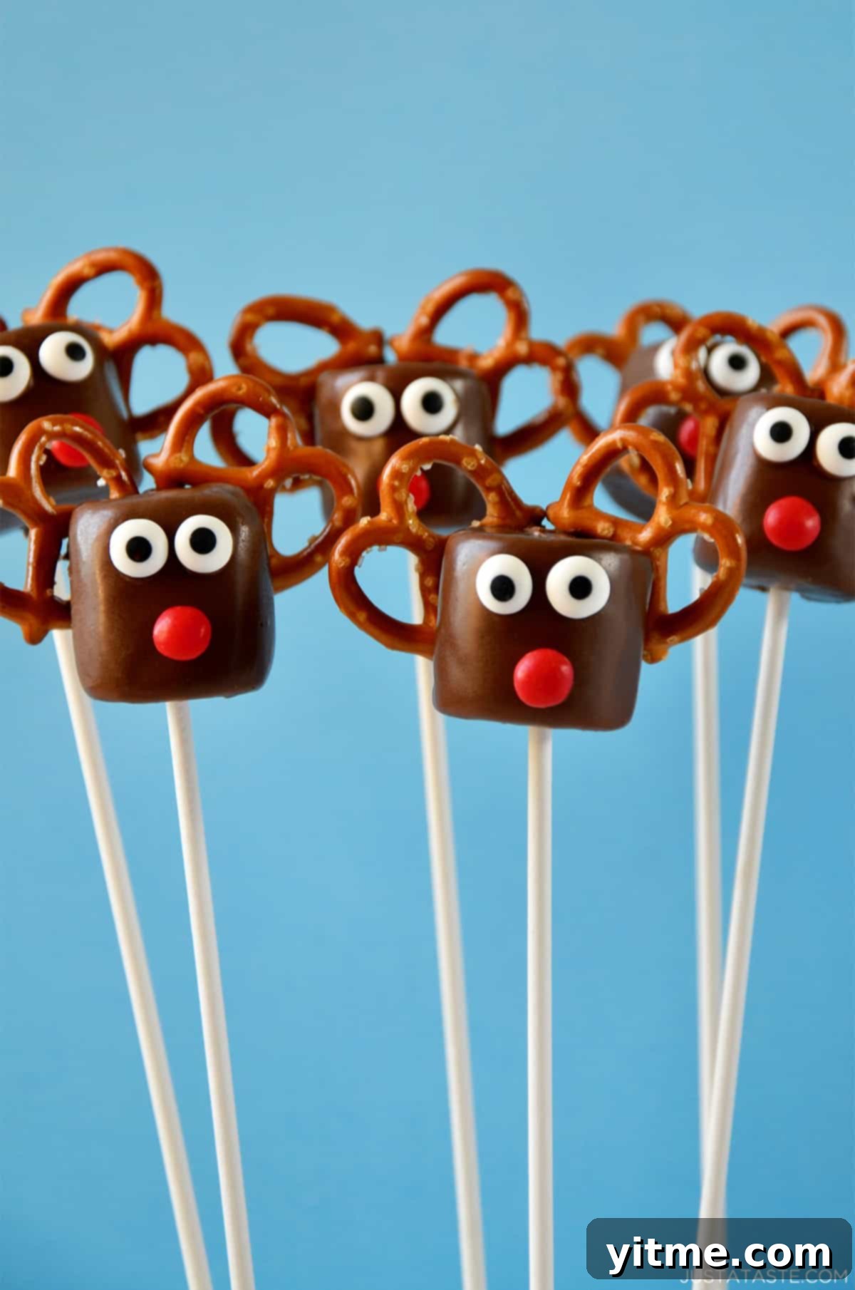 Chocolate-covered marshmallows transformed into adorable reindeer with candy eyes, red candy noses, and pretzel 