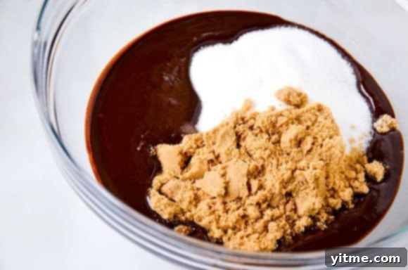 Melted chocolate, white sugar and brown sugar in a glass bowl