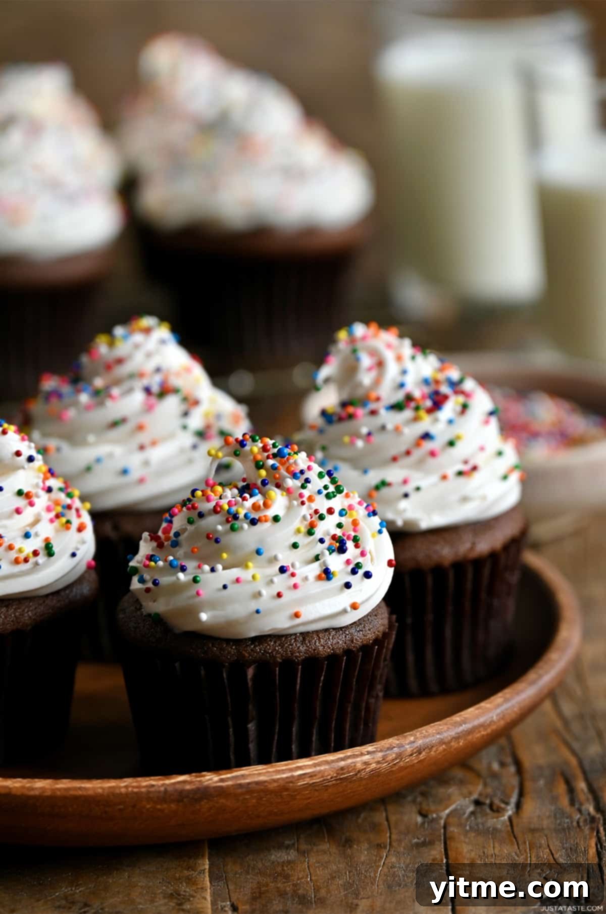 Chocolate cupcakes topped with buttercream frosting and rainbow sprinkles.