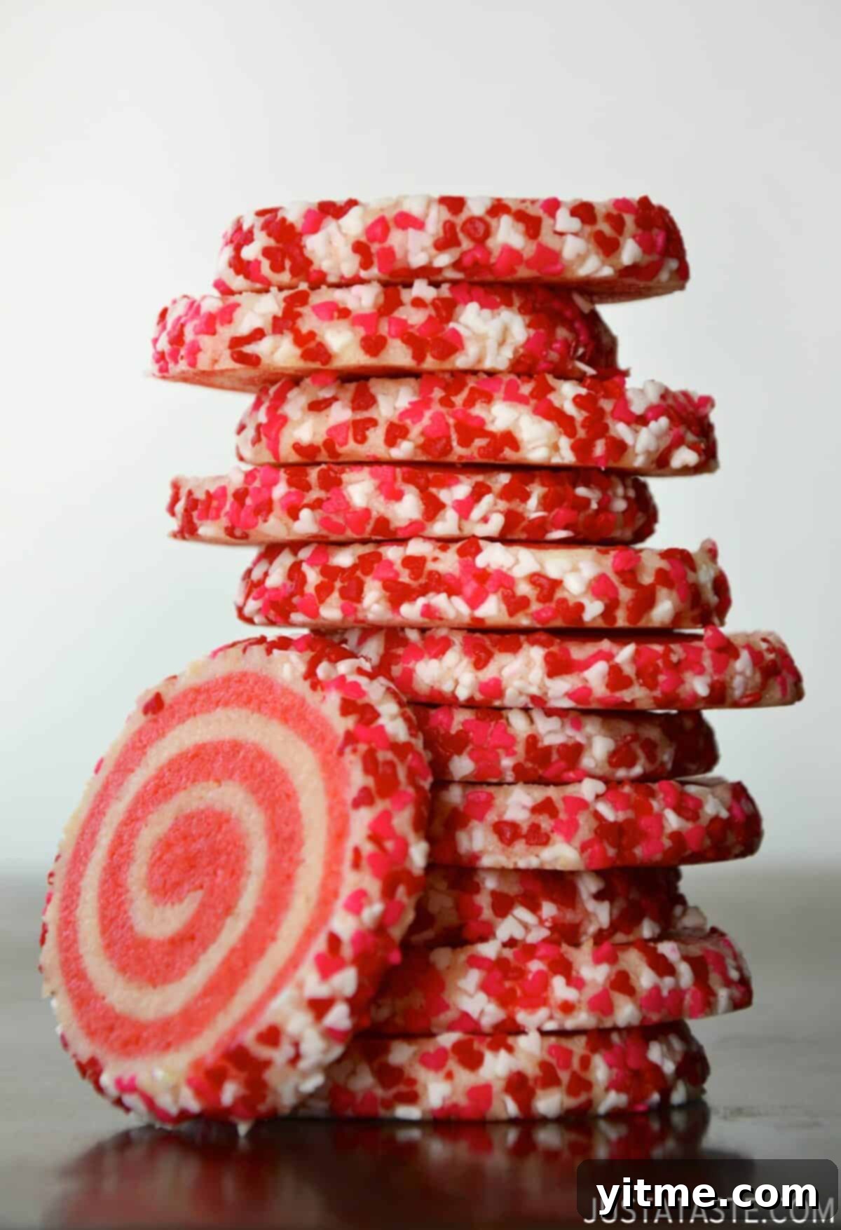 A towering stack of pink pinwheel sugar cookies, adorned with charming heart-shaped sprinkles.