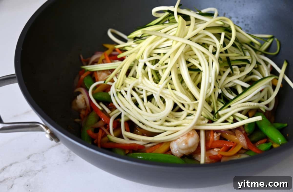 Shrimp, vegetables and zucchini noodles in a wok.