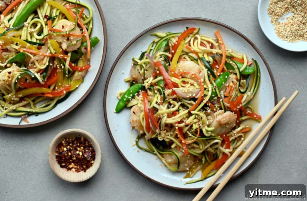Two plates of zucchini noodle stir-fry with shrimp and chopsticks.