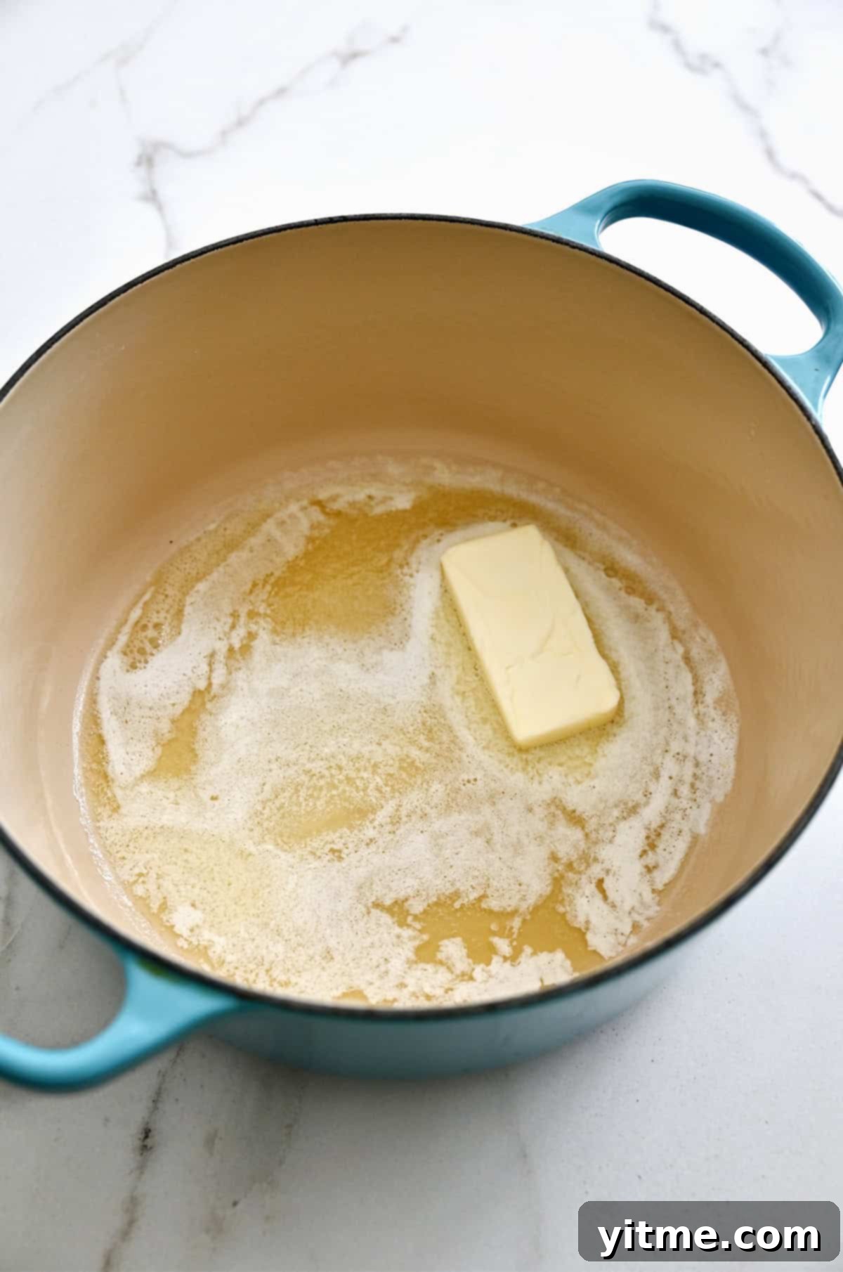 Adding flour to a stockpot with melted butter