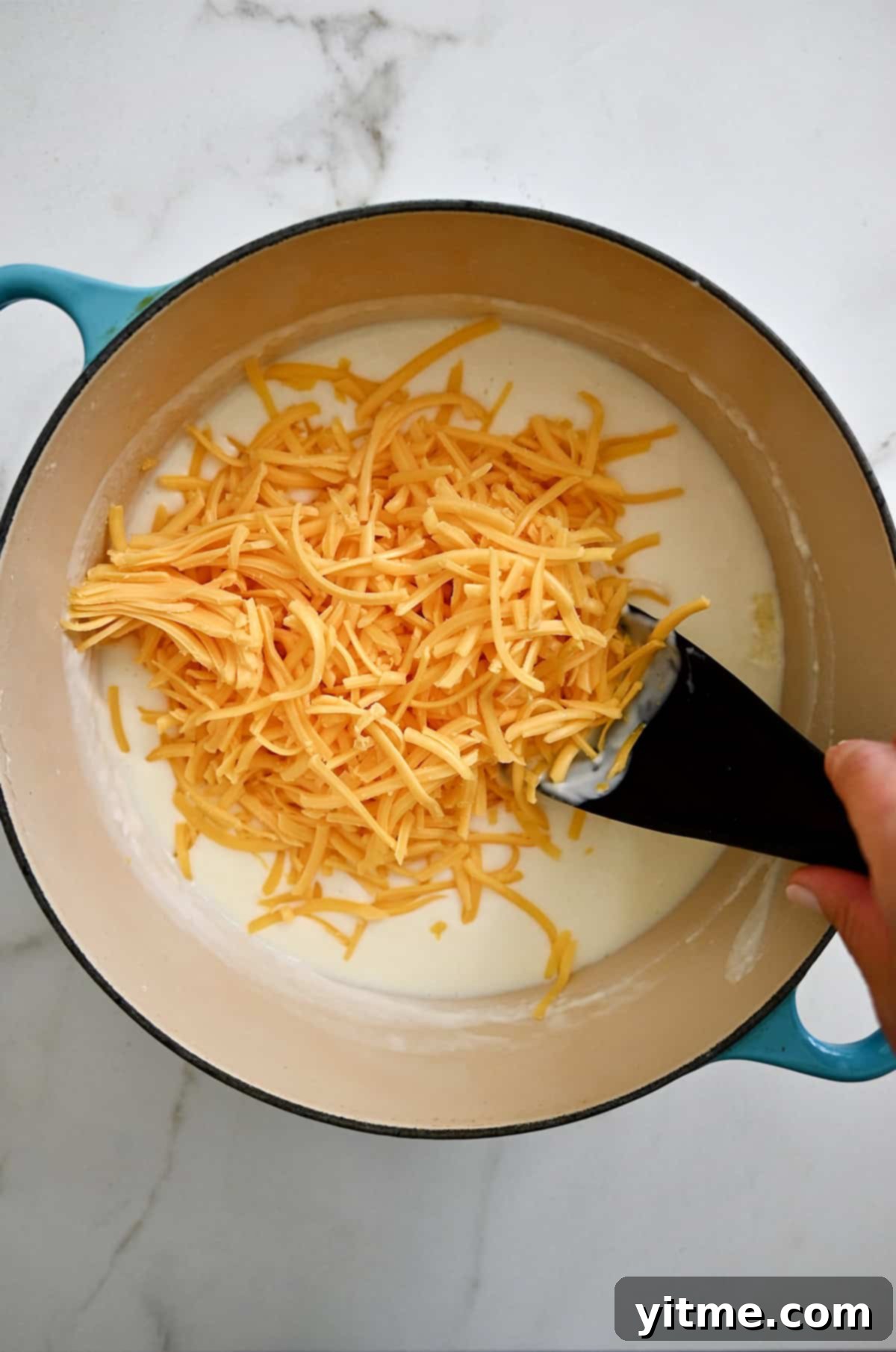 Adding cheddar cheese to a thick milk base