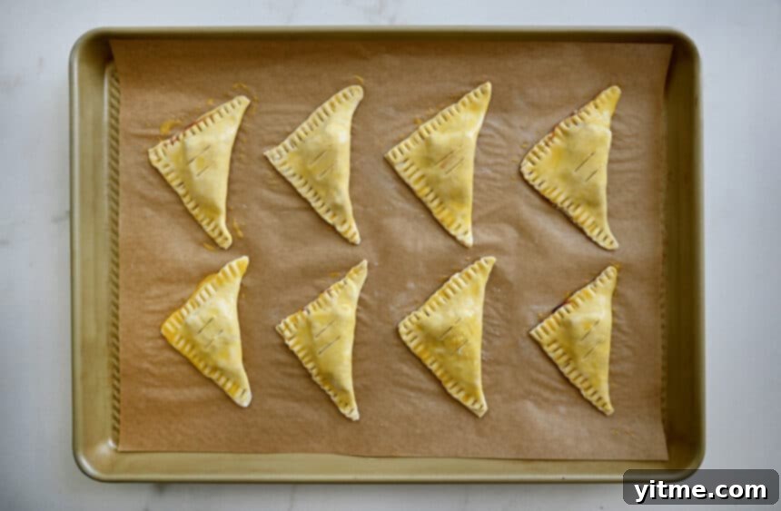 Unbaked puff pastry triangles on a baking sheet