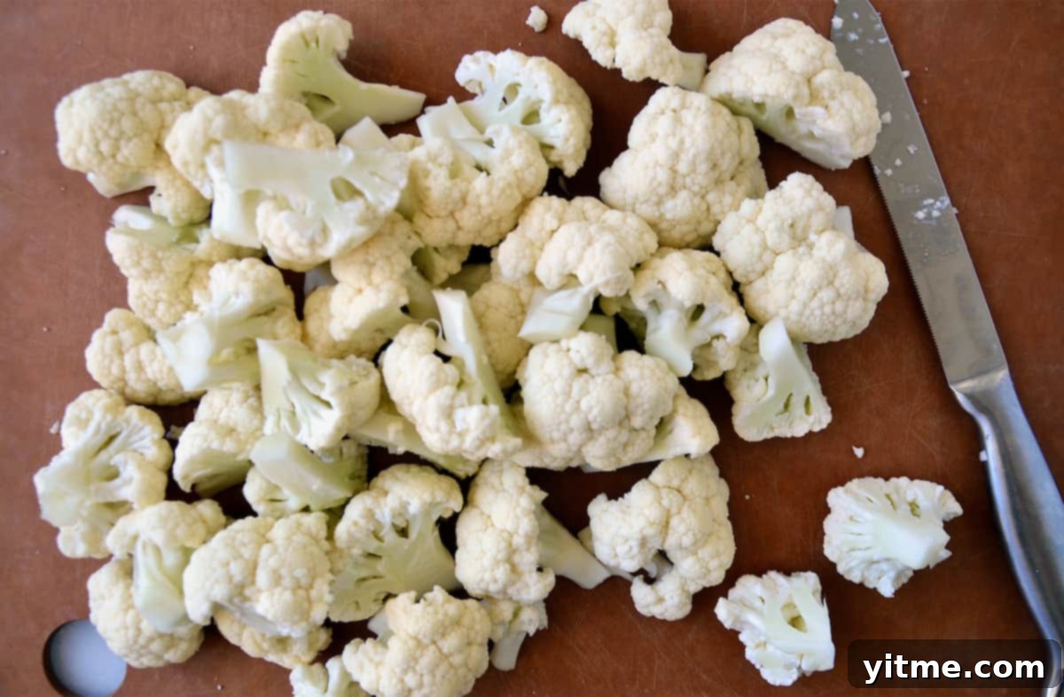 Cheesy Chive Mashed Cauliflower 3 Cauliflower florets on a cutting board. A knife is beside the florets.
