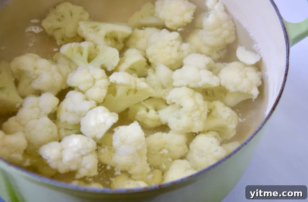 Cheesy Chive Mashed Cauliflower 4 Cauliflower florets submerged in water in a Dutch oven.