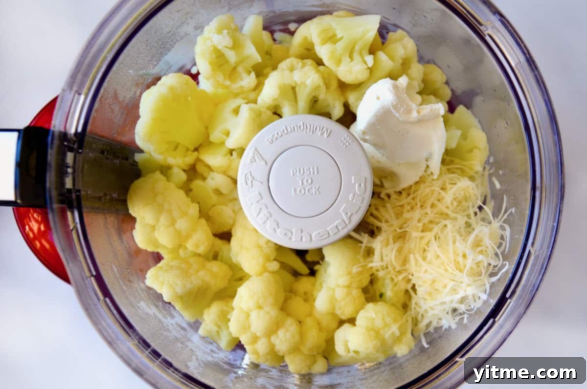 Cheesy Chive Mashed Cauliflower 5 Cauliflower florets, grated cheese and cream cheese in the bowl of a food processor.