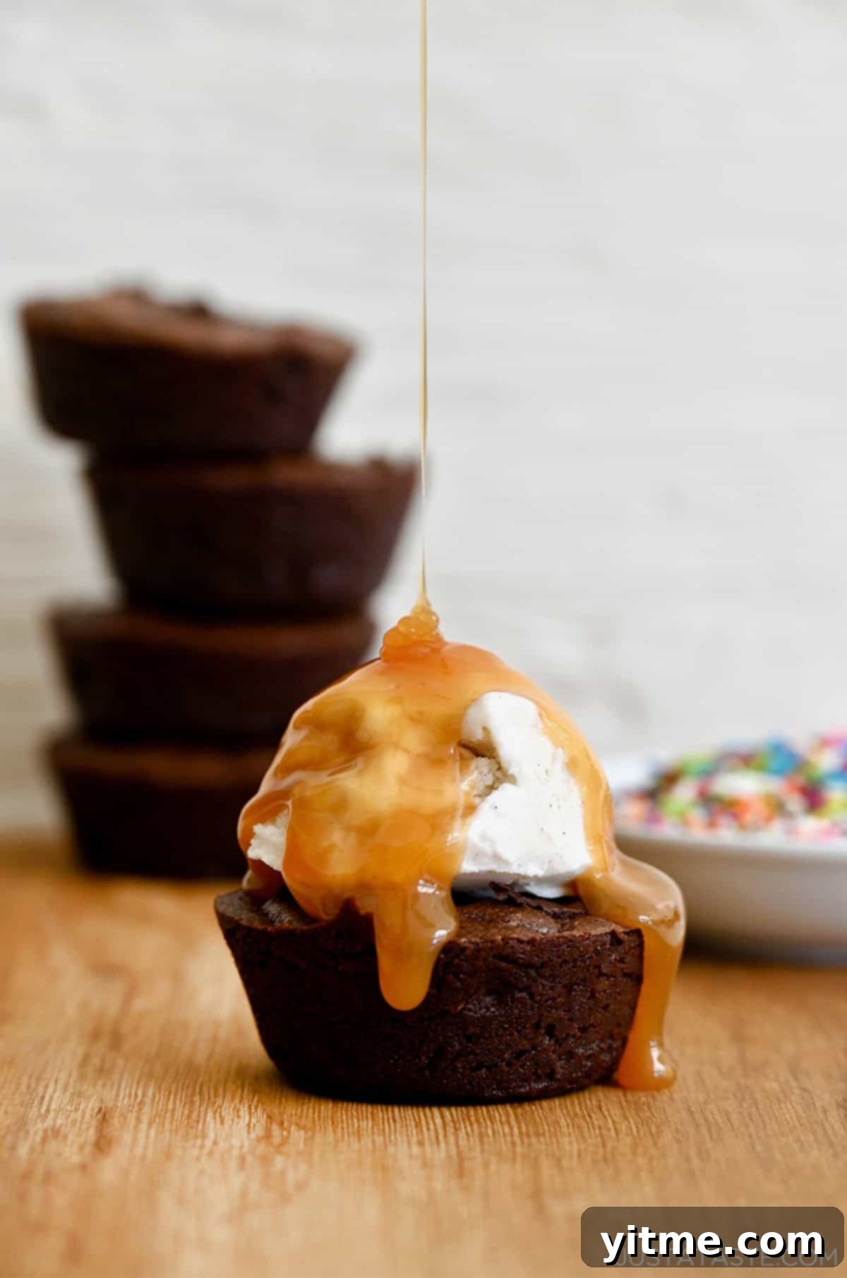 A fudgy brownie cupcake topped with vanilla bean ice cream and a thick drizzle of caramel sauce.