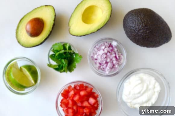 Freshly prepared Greek Yogurt Guacamole in a bowl, showing its creamy texture and visible pieces of red onion and tomato.