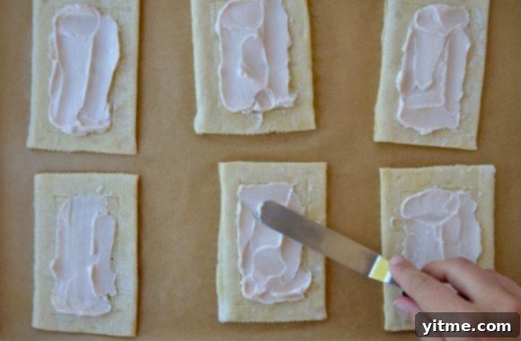 Strawberry cream cheese jam being spread onto puff pastry