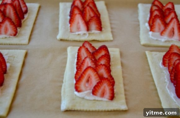 Sliced strawberries in rows on top of cream cheese pastry