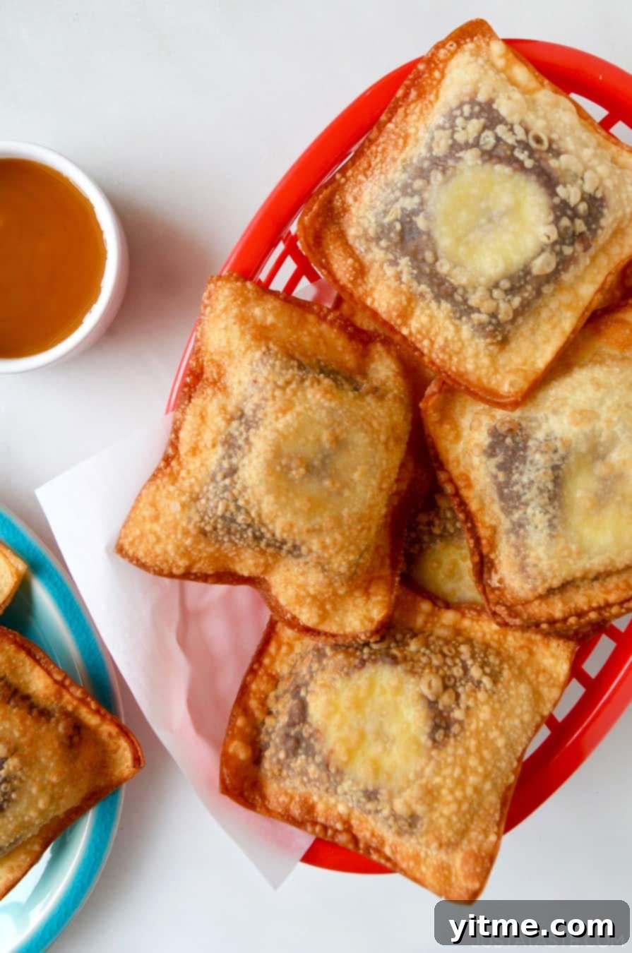 Banana Chocolate Wonton Poppers in a red food basket next to a small bowl filled with caramel sauce