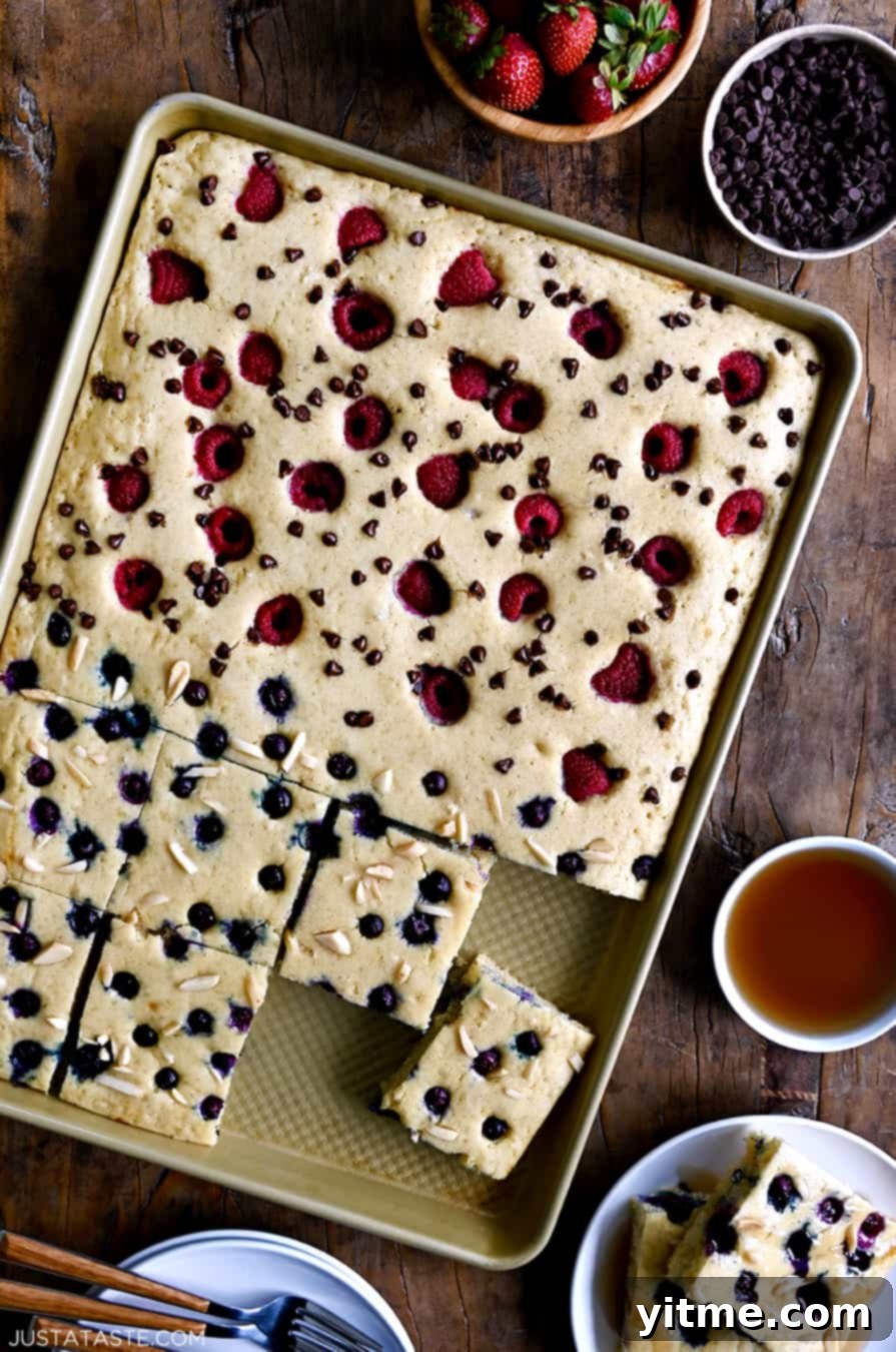 A top-down view of sheet pan pancakes topped with fresh berries and nuts.