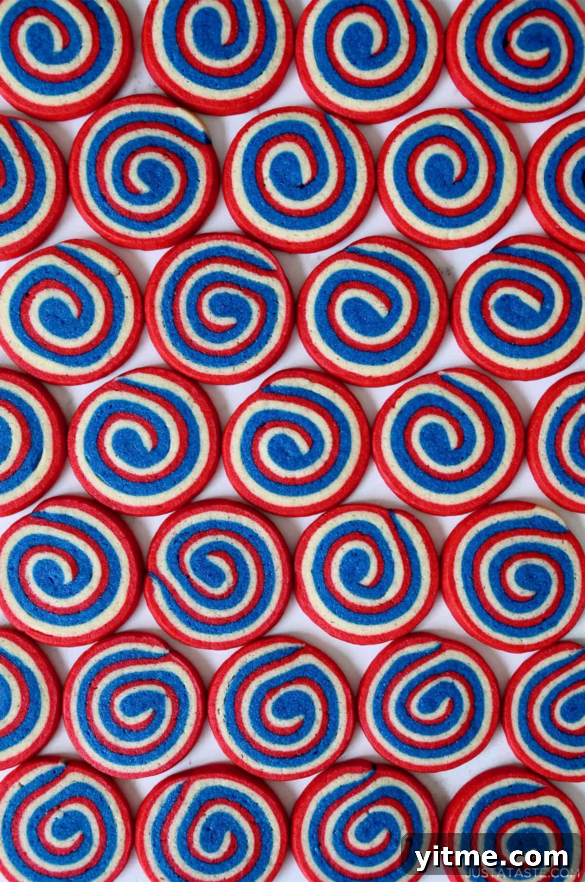 A top-down view of rows of red, white and blue pinwheel icebox cookies, perfect for patriotic celebrations.