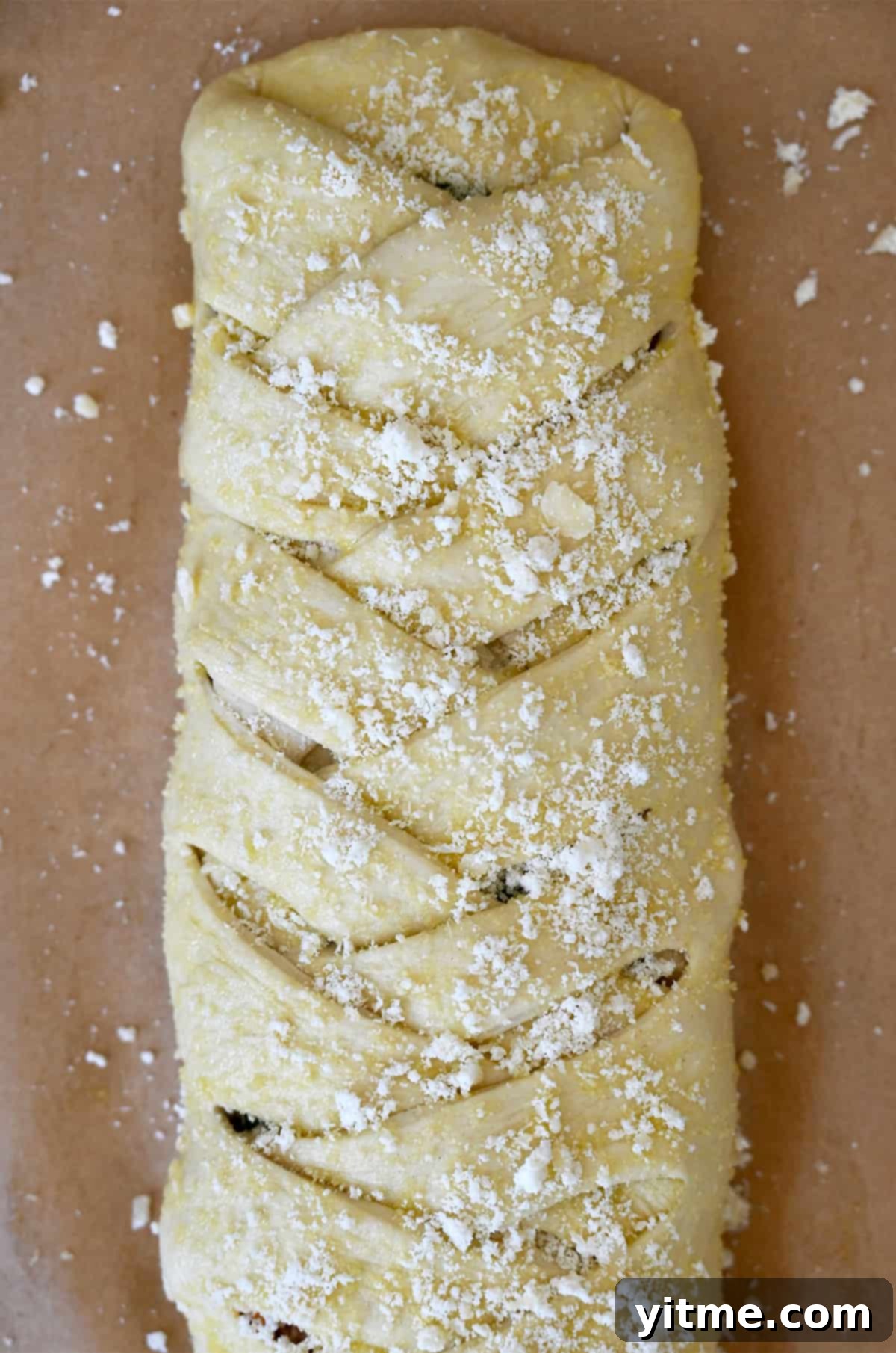 Unbaked Stromboli sprinkled with grated Parmesan cheese on a parchment paper-lined baking sheet.